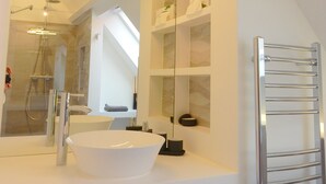 A modern bathroom with a large mirror, a white sink, and a glass-enclosed shower.