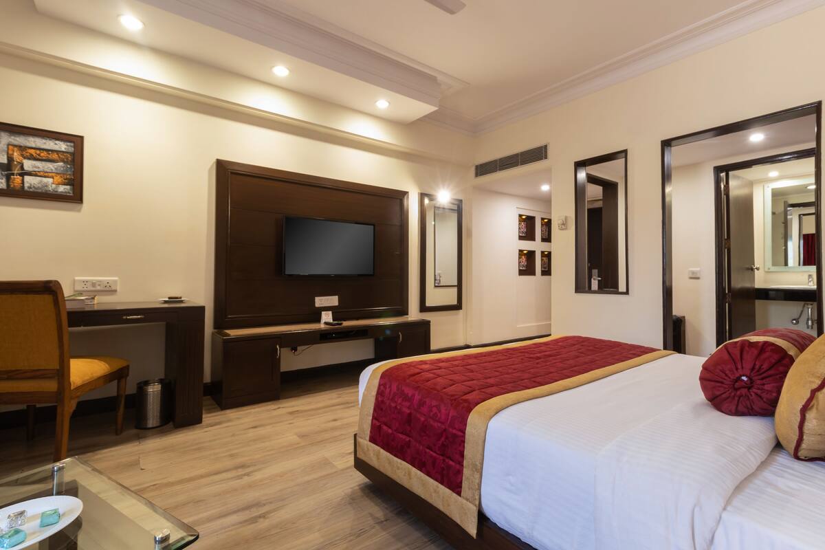 A hotel room with a bed, a desk, a television, and a mirror.