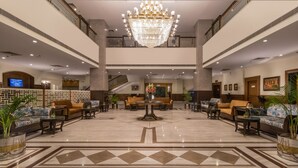 Un'ampia hall con un sontuoso lampadario, diverse zone relax e una composizione floreale al centro.