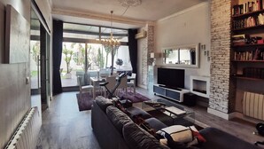 Un soggiorno moderno con un ampio divano componibile, una TV a schermo piatto e un'area pranzo con tavolo e sedie.