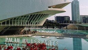 Un edificio moderno dal design architettonico unico e dalle linee curve, con area piscina e la scritta “PALAU DE LES ARTS” sullo sfondo.