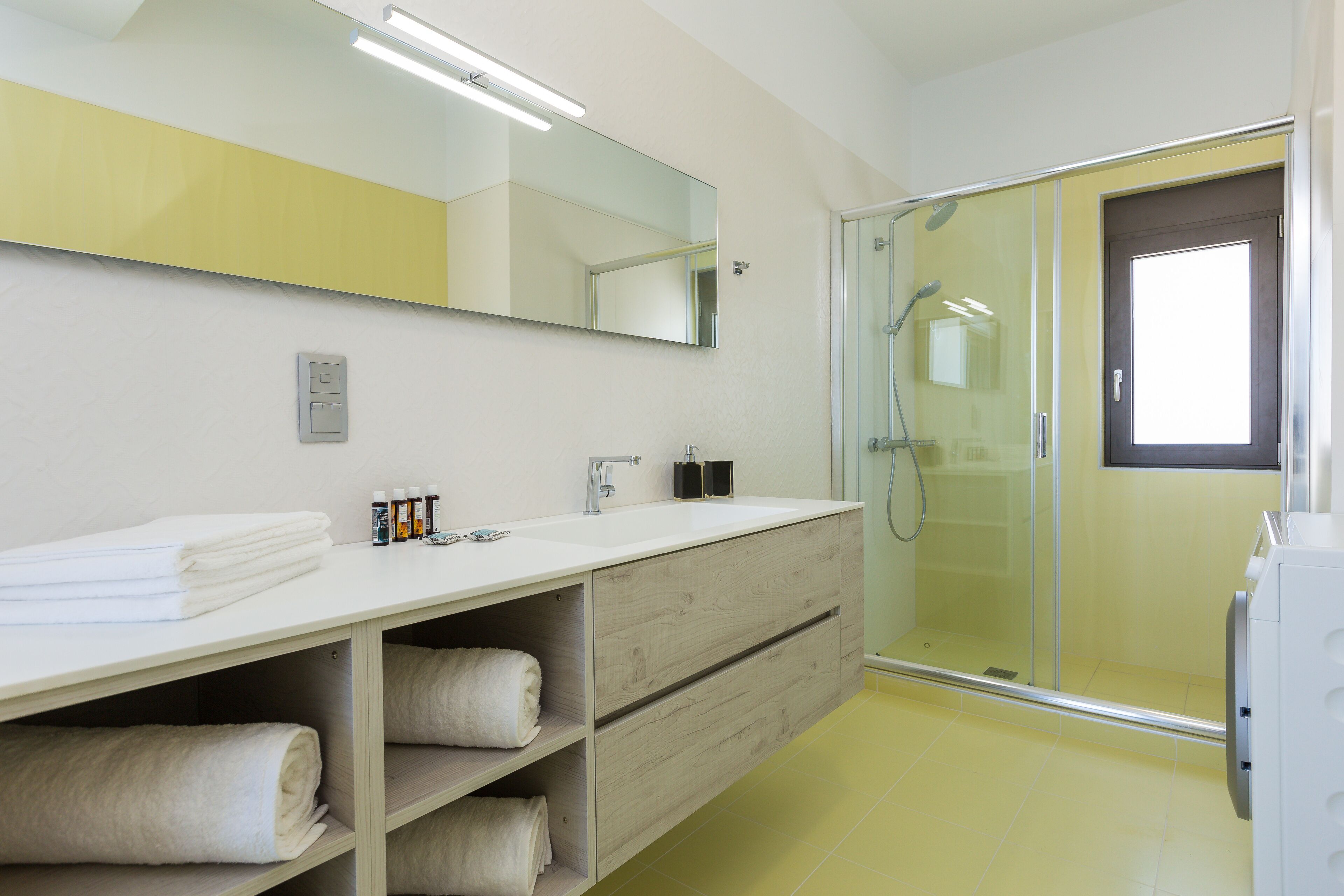 Une salle de bain moderne avec un meuble-lavabo blanc, une cabine de douche en verre et un grand miroir.