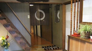 Ein traditionelles japanisches Interieur mit einer Holztreppe, einem Schuhregal und einem kleinen Topfpflanzen.