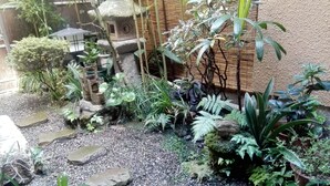 Ein Garten mit verschiedenen Pflanzen, Steinen und einer Steinslatern.