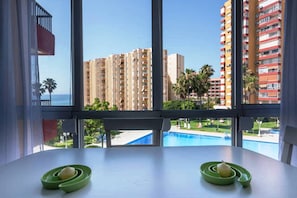 A room with a view of a swimming pool and high-rise buildings.