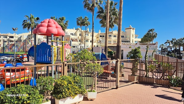 Un parque infantil con estructuras de juego coloridas y palmeras.