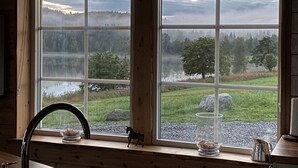 Una cocina con un ventanal que da a un paisaje boscoso y un lago.