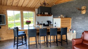 Una cocina moderna con salpicadero de piedra, armarios de madera y una zona de bar con taburetes.