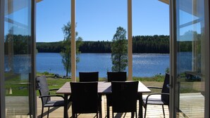 Un espacio al aire libre cubierto con una mesa y sillas frente a un lago.