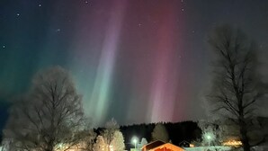 Una cabaña con un paisaje nevado y una aurora visible en el cielo nocturno.