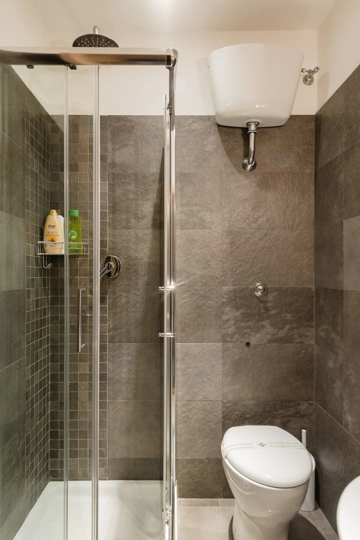 Ein modernes Badezimmer mit einer Duschkabine, einer weißen Toilette und einem wandmontierten Waschbecken.