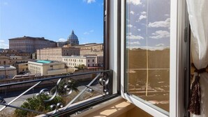 Un balcon offrant une vue sur un grand bâtiment surmonté d’un dôme, ainsi que sur d’autres bâtiments historiques et un ciel dégagé.