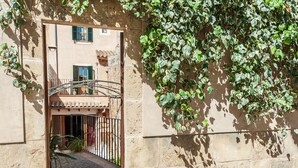 Un bâtiment en pierre doté d’un portail en fer forgé, d’un chemin pavé et d’un balcon surmonté d’un toit en tuiles.