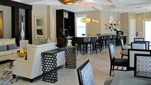 Un comedor amplio con techos altos, iluminación moderna y diversas opciones de asientos, incluyendo taburetes de bar y mesas de comedor.