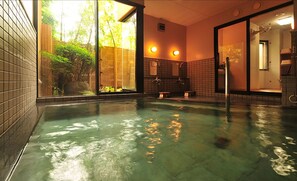 A swimming pool with clear water, a tiled floor, and a view of greenery outside. - Bouzantei Kotobuki (Ueda)