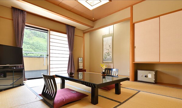 A traditional Japanese-style room with tatami flooring, a low table, a television, and sliding doors. - Bouzantei Kotobuki (Ueda)