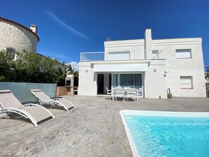 A modern villa with a swimming pool, outdoor seating, and a stone wall. - Agi Cap Llarg 9 Casa for rent in Roses Girona. (Roses)