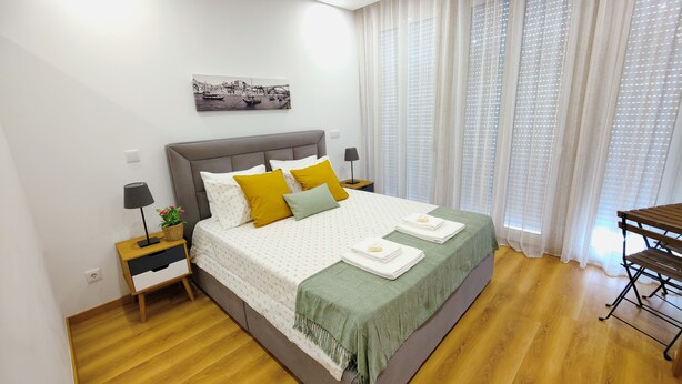 A neatly arranged bedroom with a bed, bedside tables, a lamp, and a painting on the wall. - Apartment in the Historic Center of the city, with balcony, air conditioning (Porto)