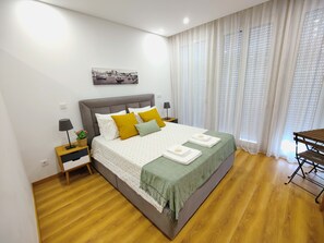 A neatly arranged bedroom with a bed, bedside tables, a lamp, and a painting on the wall. - Apartment in the Historic Center of the city, with balcony, air conditioning (Porto)