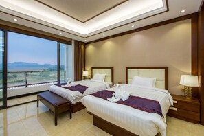 Een hotelkamer met twee bedden, een bankje en een groot raam met uitzicht op de bergen.