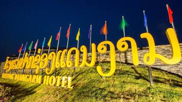 A hotel sign with multiple flags and the name "Taksong Danni CARM HOTEL" in large yellow letters.