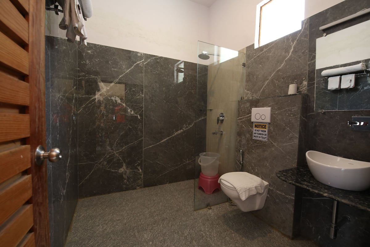 A modern bathroom with a glass-enclosed shower, a white sink, and a marble-tiled wall.