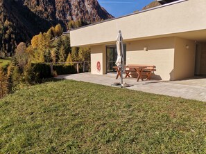 Un bâtiment moderne doté d’un patio, d’un banc en bois et d’une table.