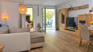 A modern living room with a sofa, TV, and dining area. - Strandküken, Germany (Breege)