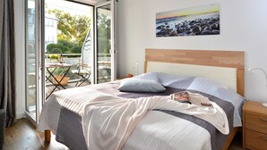 A bedroom with a bed, a nightstand, a painting, and a view through a glass door. - Strandküken, Germany (Breege)