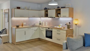 A modern kitchen with white cabinets, a built-in oven, and a countertop with a kettle and coffee maker. - Strandküken, Germany (Breege)