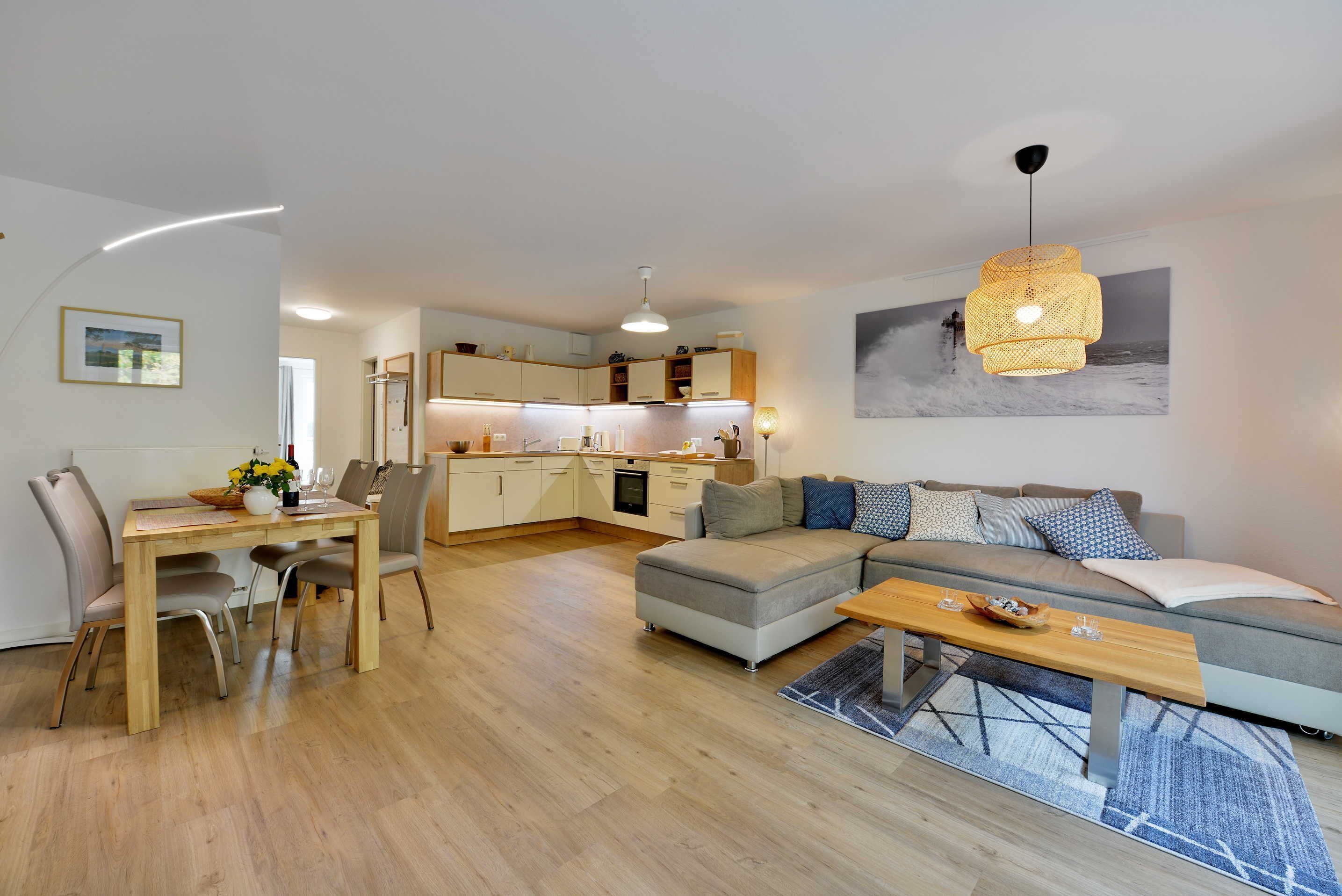A modern living room with a dining area, a kitchen in the background, and a large window.