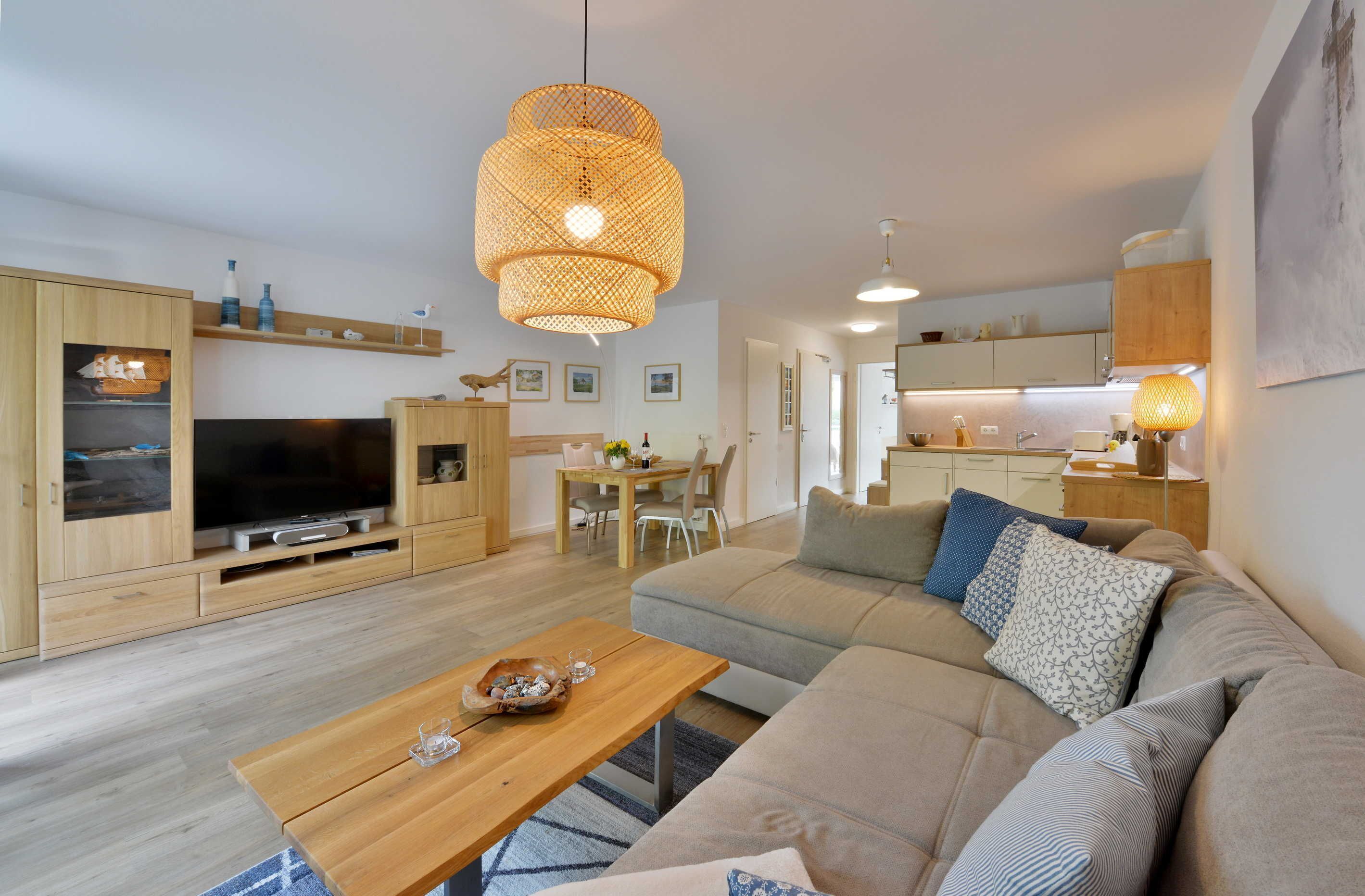 Ett modernt vardagsrum med ett TV-bord i trä, en soffa och en matplats med ett bord och stolar.