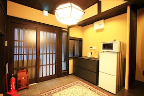 Compact kitchen with a traditional aesthetic, featuring a double-door entry, refrigerator, and modern microwave.