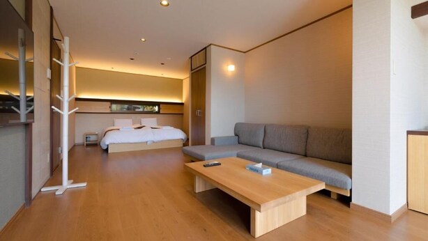 A modern hotel room with a wooden floor, a sofa, a bed, and a small table. - KumoMachiya Suieikaku (Kyoto)