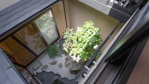 A small courtyard with a stone lantern, a large potted plant, and a small garden area with rocks and plants. - KumoMachiya Suieikaku (Kyoto)