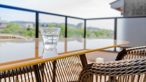 A glass of water on a glass table with wicker chairs, overlooking a cityscape. - KumoMachiya Suieikaku (Kyoto)