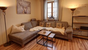 Ein gemütliches Wohnzimmer mit einem braunen Ledersofa, einem Glastisch und einem Bild eines Rehs an der Wand.