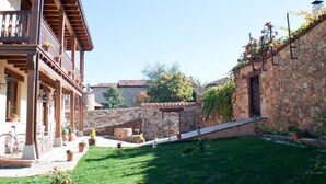 Un patio con un muro de piedra, un balcón de madera y una bicicleta.