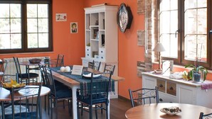 Un comedor con una mesa y sillas de madera, un armario blanco y un ventanal con vistas a árboles.