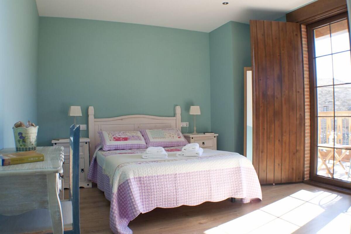 A bedroom with a bed, bedside tables, a chair, and a window with a view.