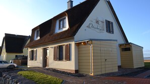 A two-story house with a steeply pitched roof, a chimney, and a sign that reads 'Ostseebier.' - Boddenbrise Vacation Rental - General Suite (Breege)