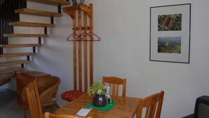 A dining area with a wooden table, chairs, a vase with flowers, and a staircase. - Apartment 1 - Apartments Meyer (Bollewick)