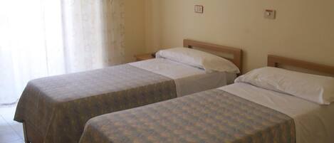 Two single beds with wooden headboards in a room with a plain wall and a framed picture.