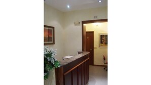A reception area with a wooden counter, a framed picture on the wall, and a door leading to another room.