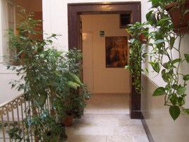 Un corridoio con piante in vaso, una porta con il segnale di uscita e un quadro appeso al muro.