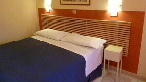 A hotel room with a bed, a nightstand, and a painting on the wall.