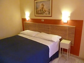 Una camera d'albergo con un letto, un comodino e un quadro appeso al muro.