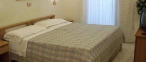 A hotel room with a bed, a nightstand, a desk, and a chair.