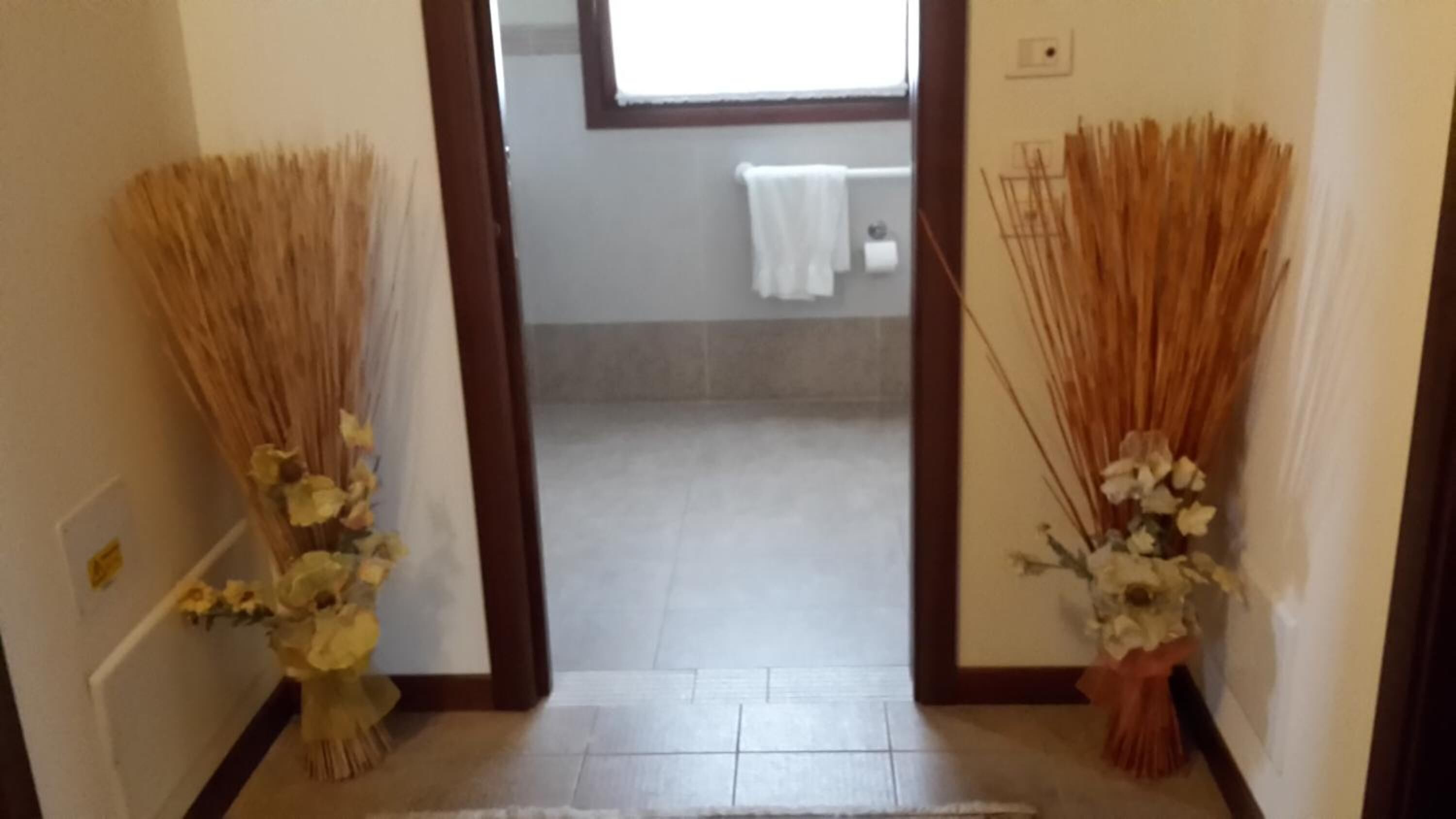 A hallway with a tiled floor leading to a bathroom with a white towel hanging on a rack.