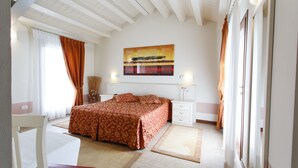 A bedroom with a bed, a chair, a nightstand, a lamp, and a painting on the wall. - Sweet Home (Treviso)